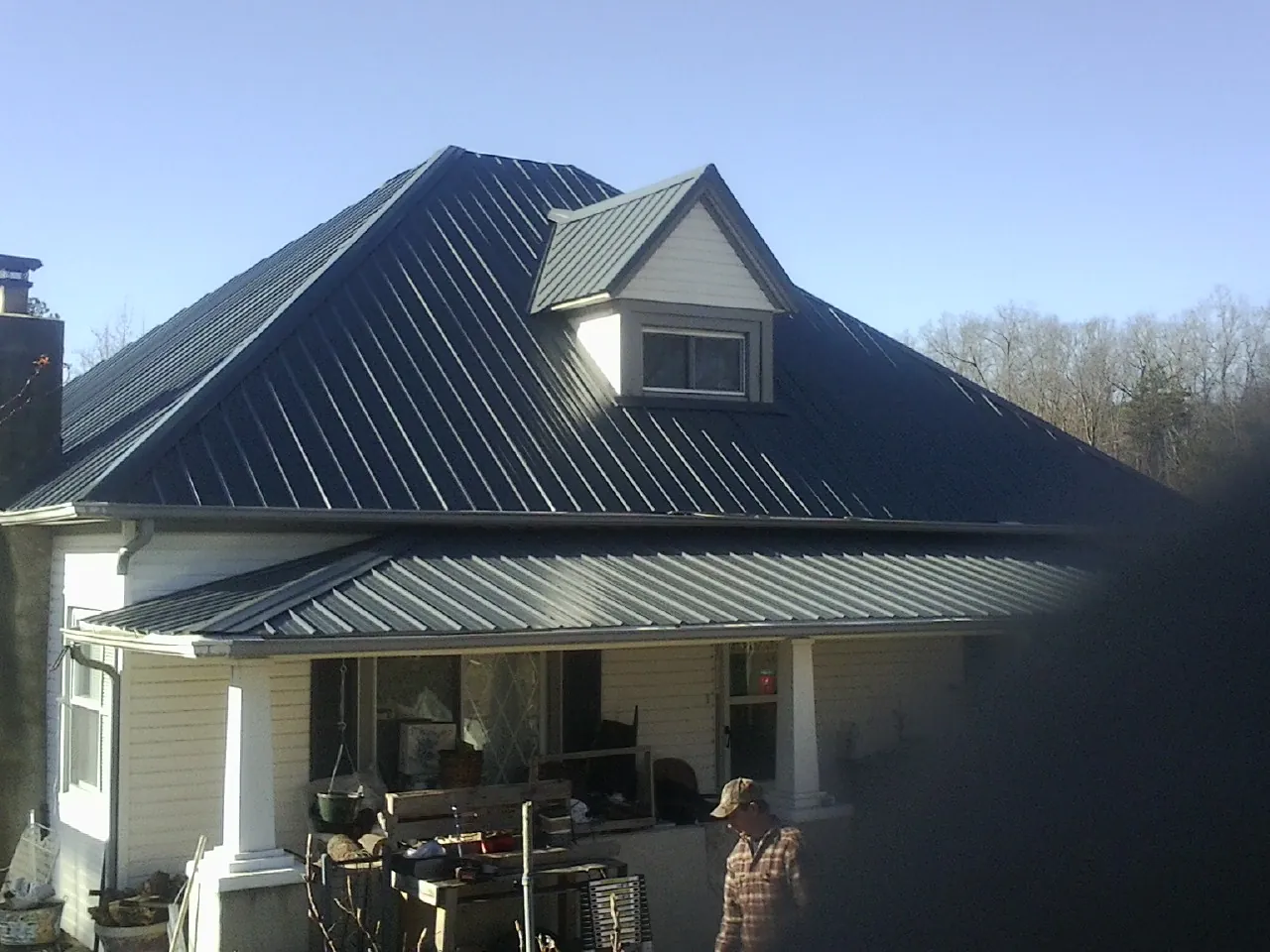 Dark blue standing seam metal roof with a dormer above a front porch in Stewartsville