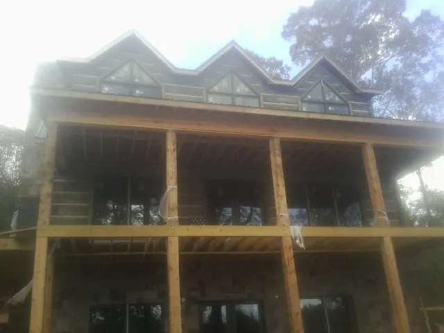 Dormers and porch framing on a large log home under construction — Roof Coating work by our crew in Stewartsville
