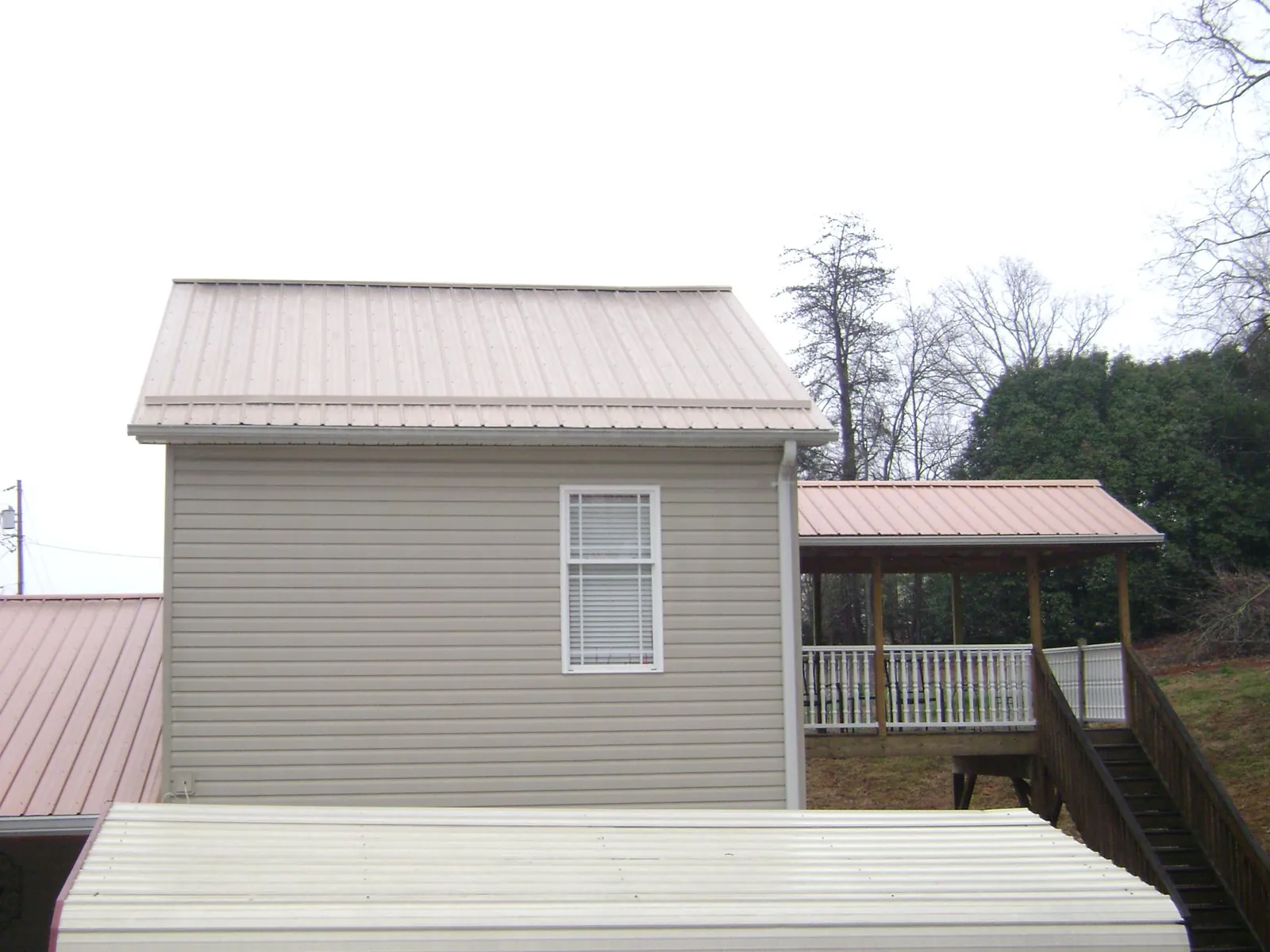 Tan metal roofs on a two story addition and attached porch, from a Roof Replacement job in Stewartsville