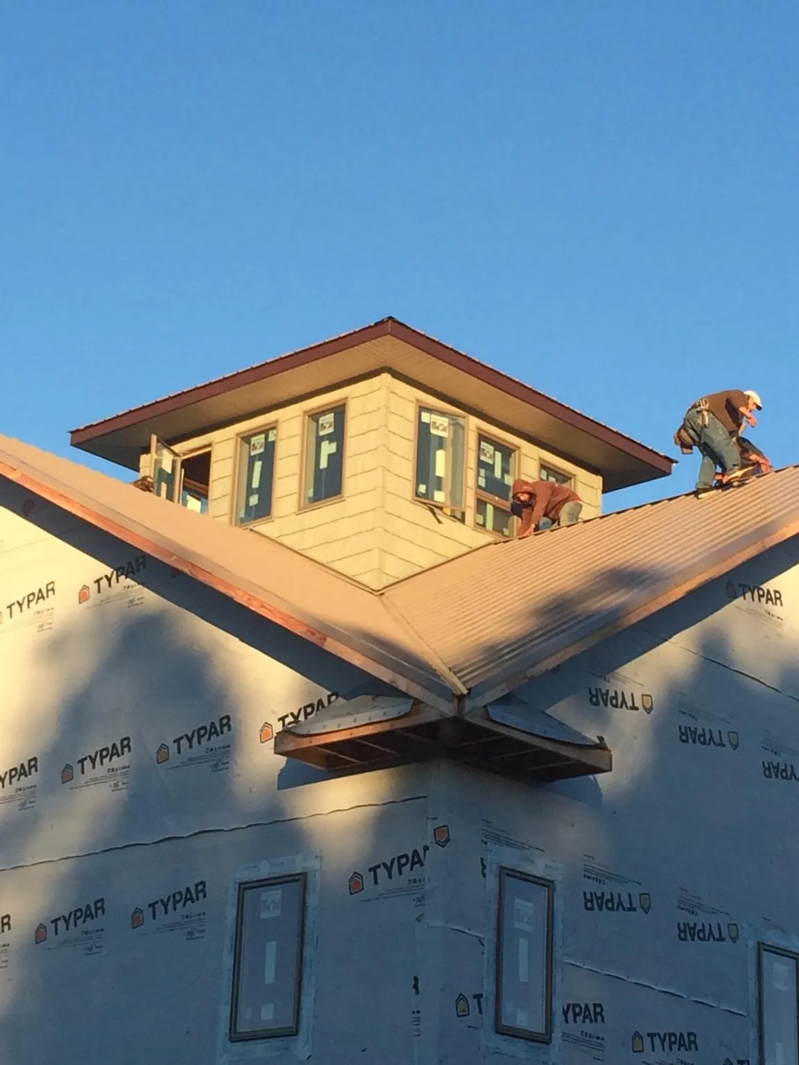 Roofers working around a rooftop cupola on a new metal roof at sunset — Roof Waterproofing in Stewartsville by Roofing Brothers